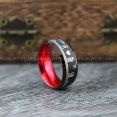 a black and red ring with white lettering on the inside is sitting next to a wooden box