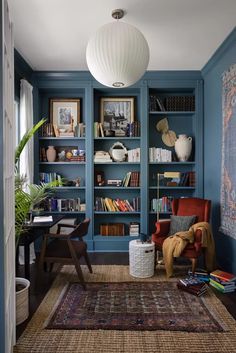 a living room with blue walls and bookshelves filled with books, plants and other items