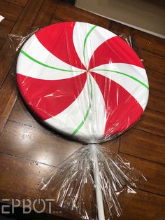 a candy cane wrapped in plastic sitting on top of a wooden floor next to a white stick