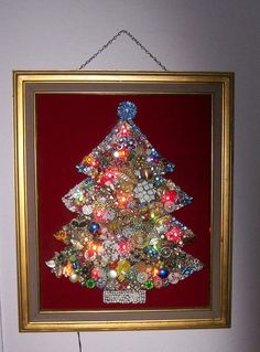 a christmas tree made out of many different types of buttons in a gold frame on a red wall