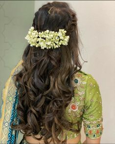 the back of a woman's head with long hair and flowers in her hair