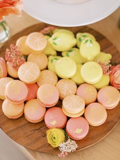 there are many different types of cookies on the wooden platter with pink and yellow frosting