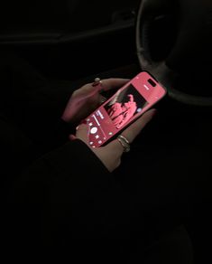 a person holding a cell phone in their hand with the screen lit up at night