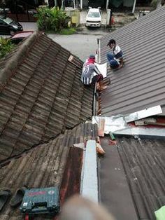 two men working on the roof of a house