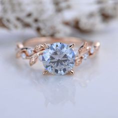 an engagement ring with a blue topazte surrounded by white and rose gold leaves