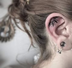 a woman's ear has a small bird tattoo on it