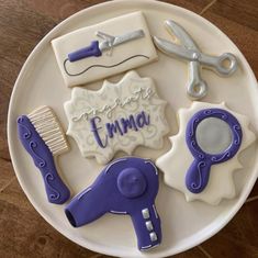 decorated cookies on a plate with scissors, combs and name written in icing