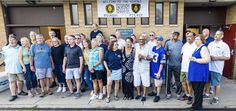 a group of people standing in front of a building with their arms around each other