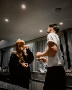 a man and woman standing in a kitchen next to each other