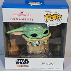 an action figure in a box with the lid open to show it's baby yoda