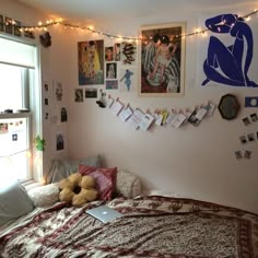 a bed room with a neatly made bed and lots of pictures on the wall above it