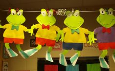 three paper frog puppets hanging from a line