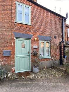 an old brick building with a green door and window on the outside, next to a planter