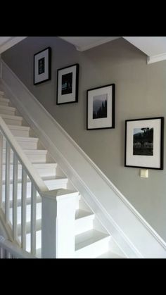 some pictures hanging on the wall next to a stair case with white railing and handrail