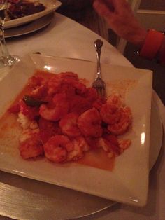 a white plate topped with shrimp and sauce