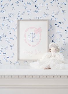 a white teddy bear sitting on top of a bed next to a framed picture and wallpaper