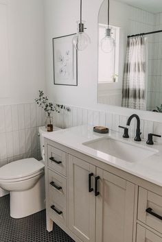 a bathroom with two sinks, a toilet and a mirror above the sink in it