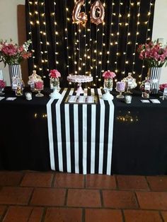 a black and white striped table cloth with pink flowers on it is set up for a 50th birthday party