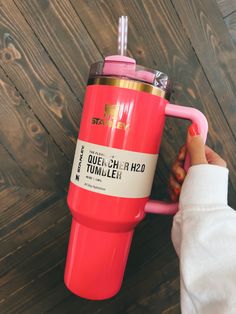 a woman is holding a pink tumbler cup