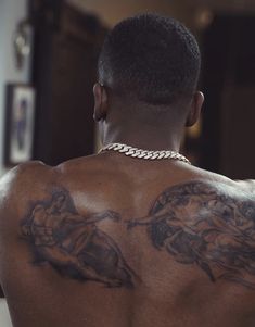 the back of a man with tattoos on his chest