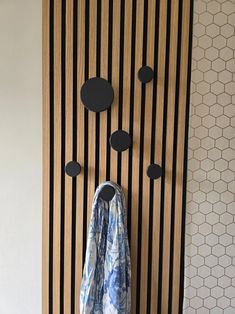 a coat hanging on the wall next to a wooden door with black knobs and circles