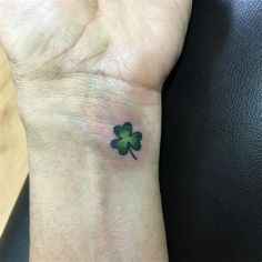 a small four leaf clover tattoo on the wrist