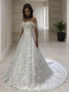 a woman in a white wedding dress standing on the floor with her hand on her hip