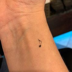 a small tattoo on the wrist of a woman's left arm with a musical note