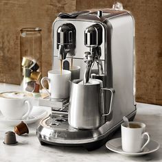 an espresso machine sitting on top of a counter next to cups and saucers