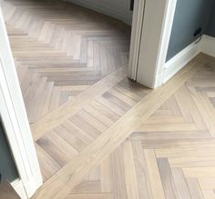 an empty room with wood flooring in the middle and door open to another room