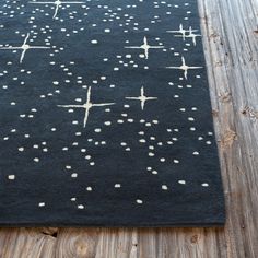 a black rug with white dots on it sitting on a wooden floor next to a wall