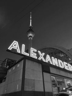 a black and white photo of a building with a neon sign that reads alexander