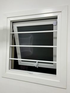 an open window with blinds on the outside and inside, in front of a white wall