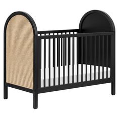 a black crib with white sheets and wicker bedding on the bottom half