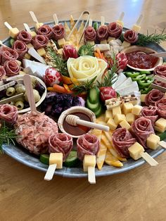 a platter filled with meats, cheeses and vegetables on skewers