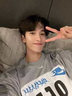 a young man laying on top of a couch holding up the peace sign with his hand