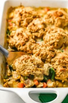 a casserole dish filled with meat and vegetables, topped with a serving spoon