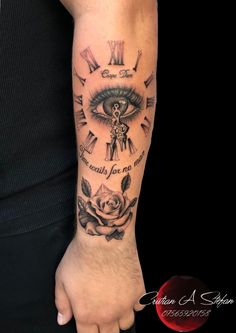 a man's arm with an eye and clock tattoo on the wrist, which has roses around it