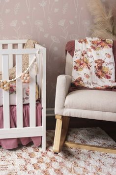 a baby crib next to a rocking chair in a room with pink wallpaper