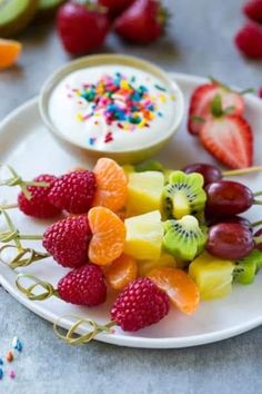 fruit skewers on a white plate with berries, kiwis and strawberries