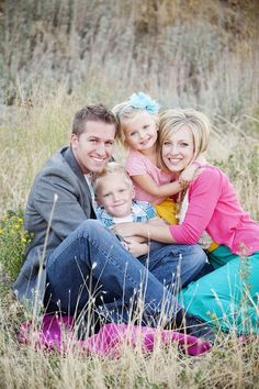 a man and woman with two children sitting in tall grass