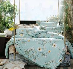 a bed with blue sheets and white flowers on it in a room next to a window