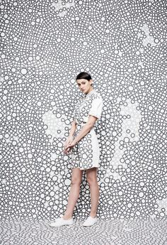 a woman standing in front of a wall with circles on it