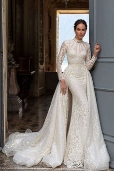 a woman in a wedding dress leaning against the wall with her hand on her hip