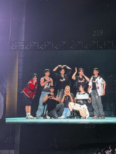 a group of people standing on top of a stage with their hands in the air