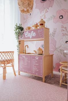 a pink and white wallpapered room with a cafe sign on the counter next to a wooden bench