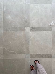 a person's feet are shown on the floor in front of a tiled wall