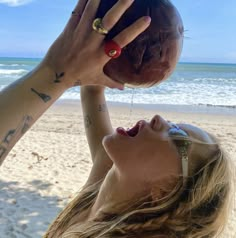 a woman on the beach holding an apple up to her face