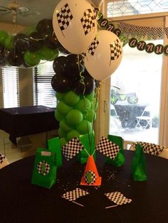 balloons and streamers are on the table at a race themed birthday party with checkered flags