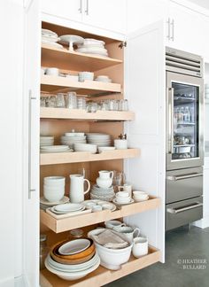 an open cabinet in a kitchen filled with dishes